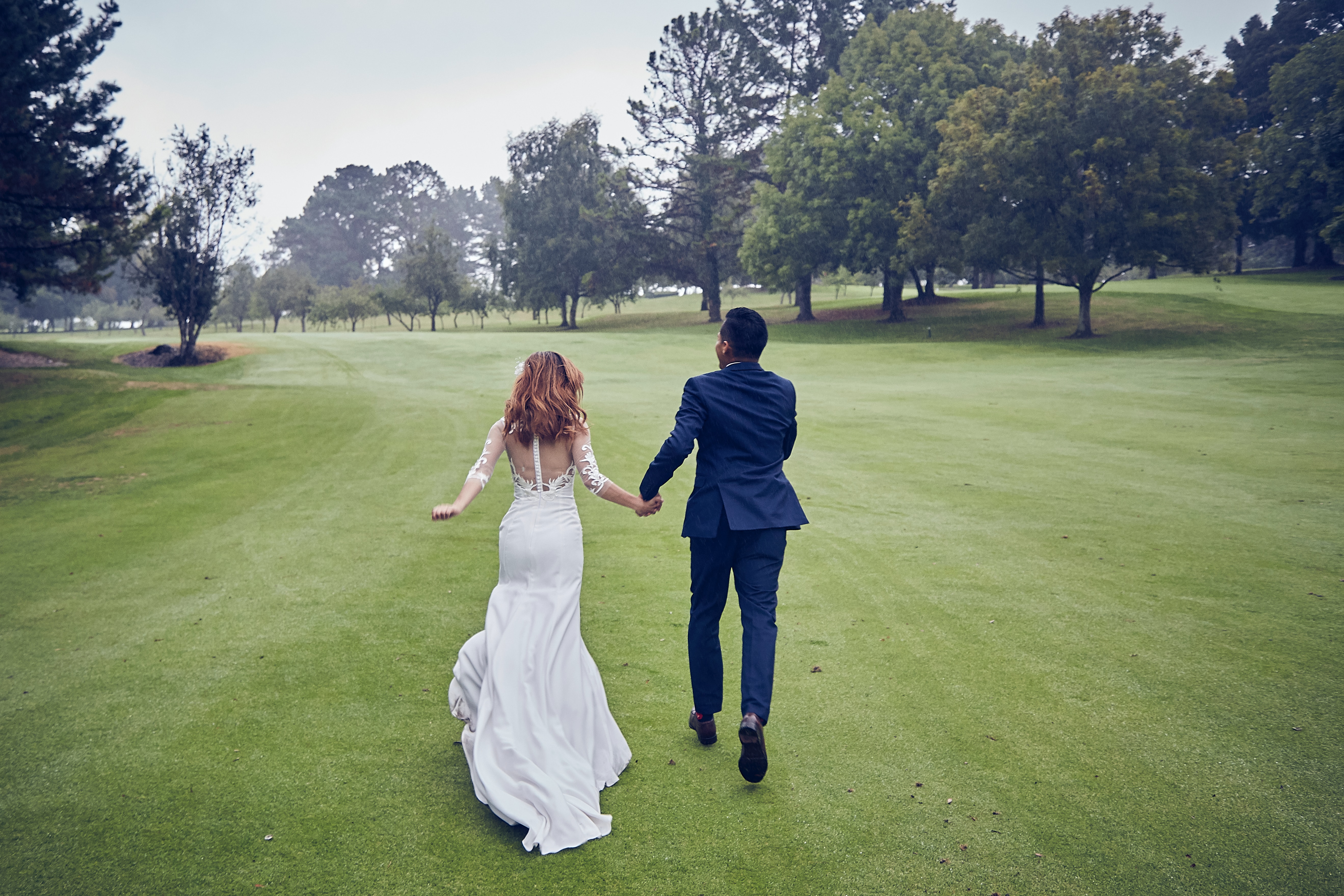 Bride and groom walking hand in hand on golf course